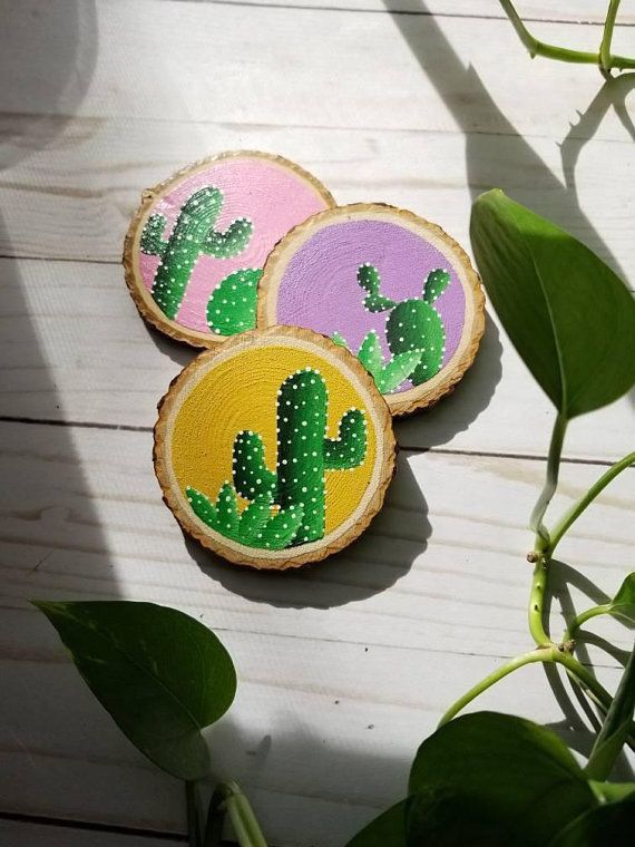 three painted wooden slices with cactus designs on them