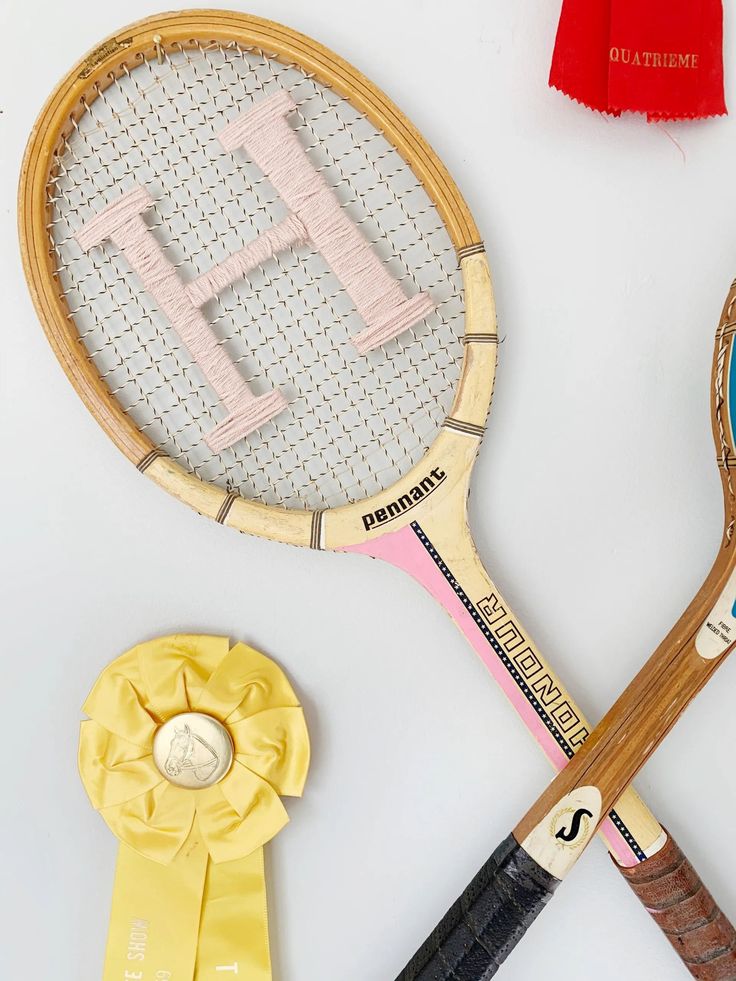 two tennis racquets, one with the letter h on it and another with an award ribbon