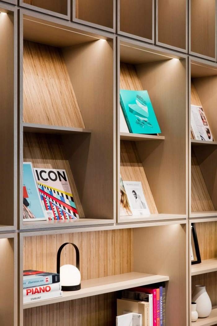 the bookshelves are lined up against the wall with wooden shelves and lamps on them