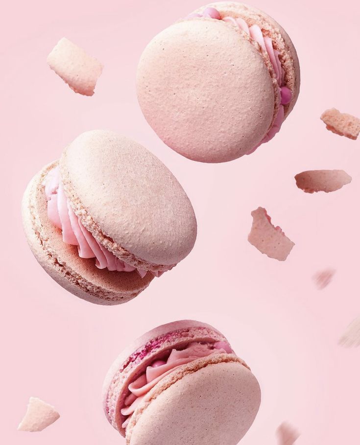 three macaroons flying in the air with pink icing