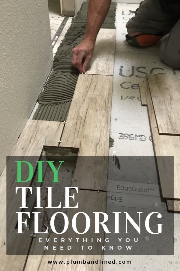 a man laying tile on top of a wooden floor