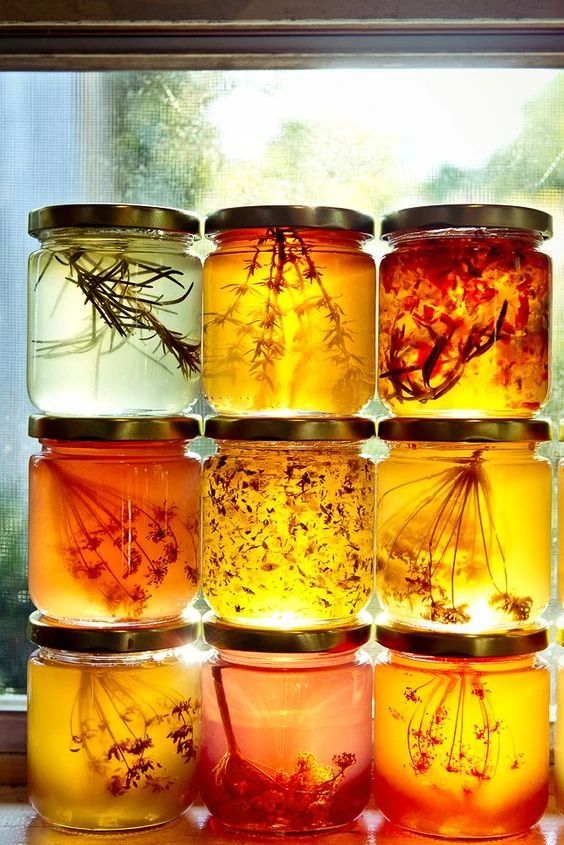 several jars filled with different types of flowers and herbs sitting on a window sill