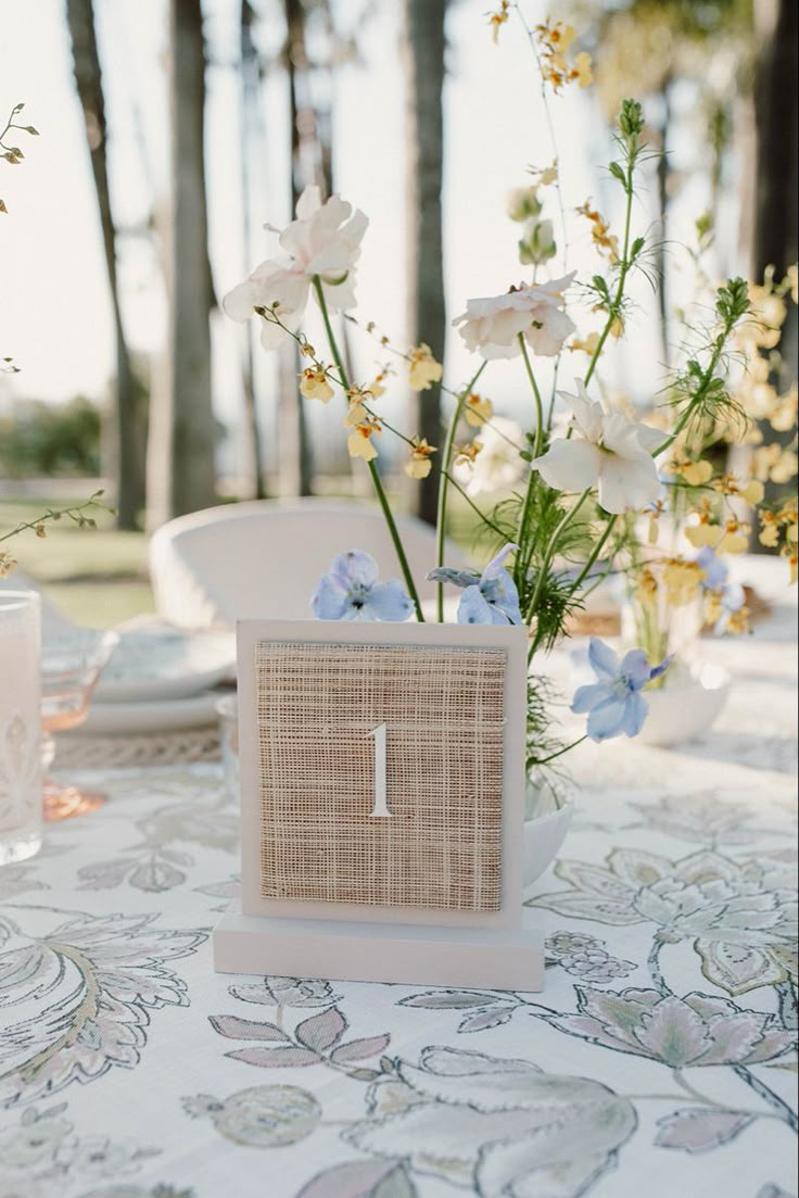 the table is set with flowers, plates and napkins for an outdoor wedding reception