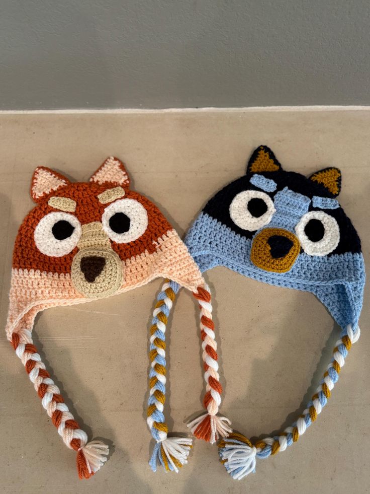 two crocheted hats with eyes and ears on top of a counter next to each other