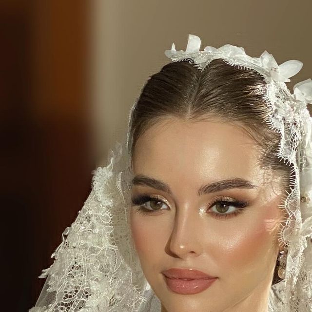 a woman wearing a veil and makeup looks at the camera