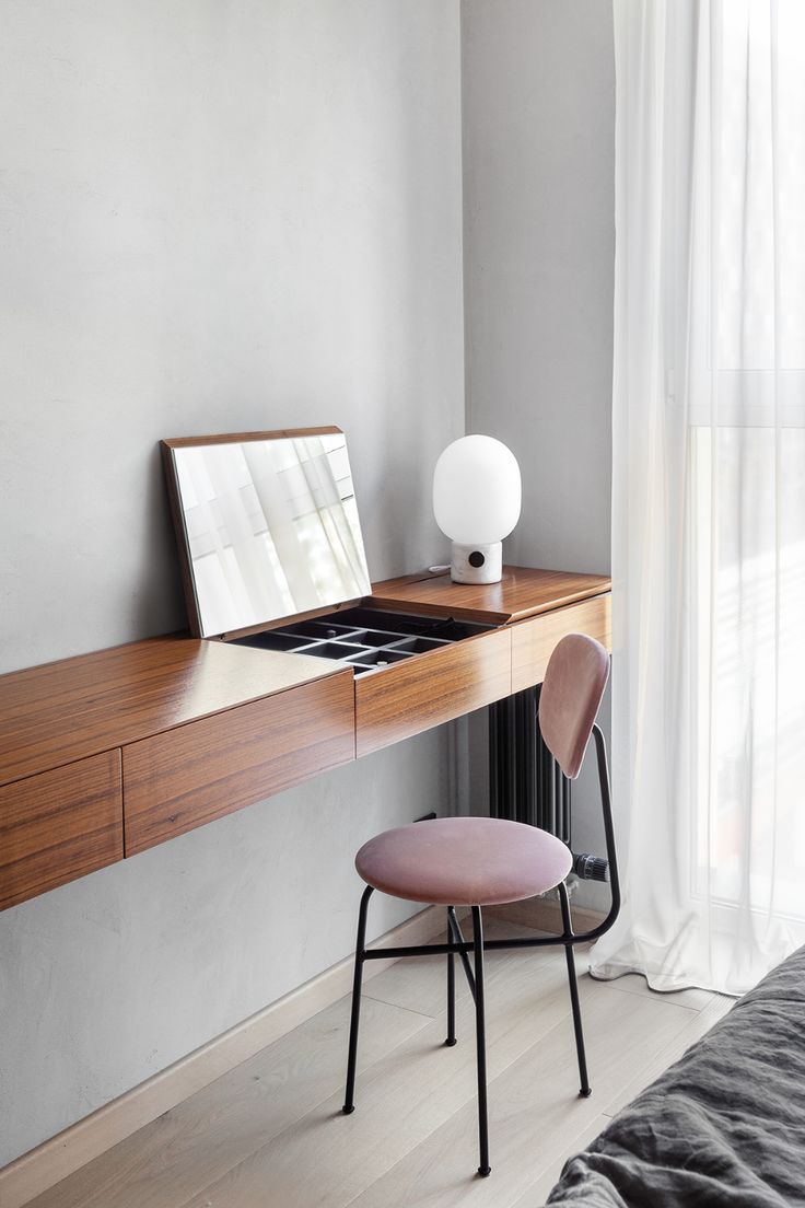 a desk with a mirror, lamp and chair