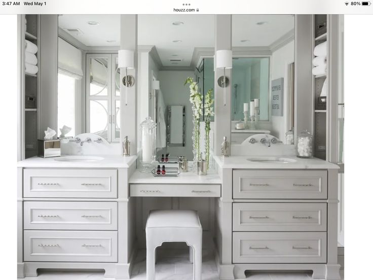 a white bathroom with two sinks, mirrors and stools in it's center