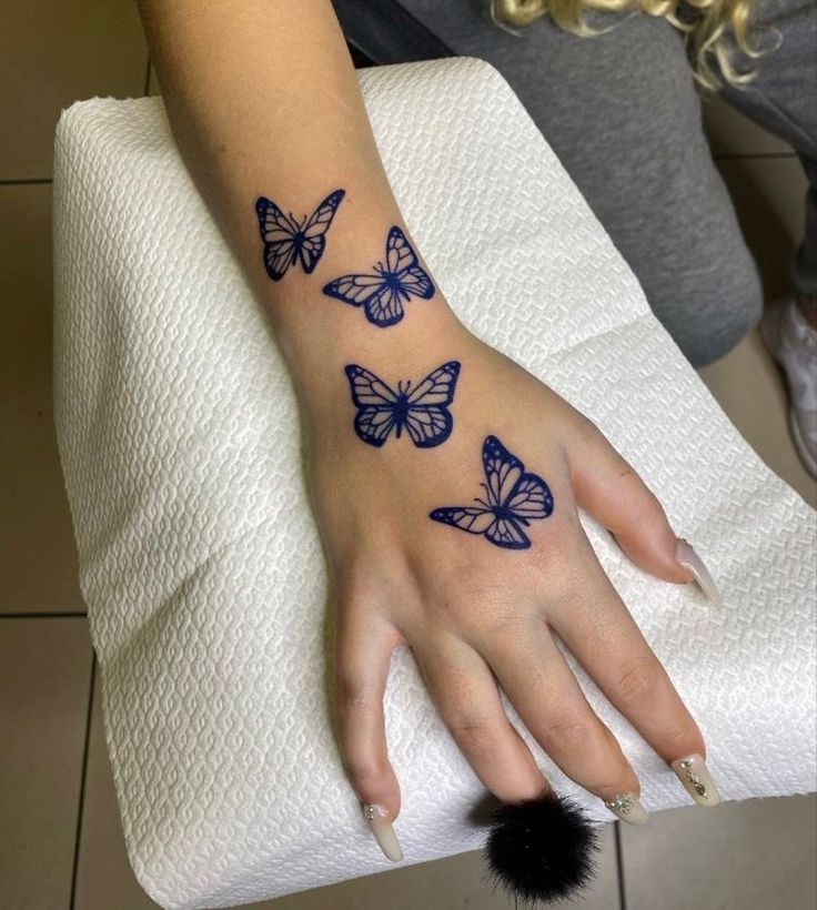 a woman's hand with blue butterflies on her left wrist and black pom - pom