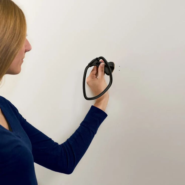 a woman is holding an object in her hand and looking at it on the wall