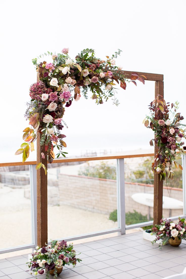 an outdoor ceremony setup with flowers and greenery on the side, overlooking the beach