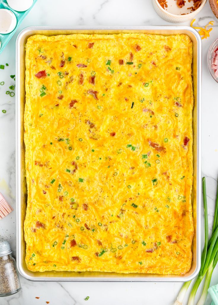 a casserole in a white dish with green onions and eggs on the side