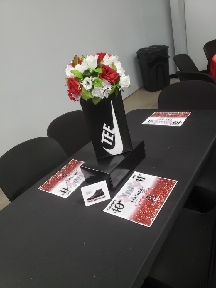 a black table topped with a vase filled with red and white flowers on top of it