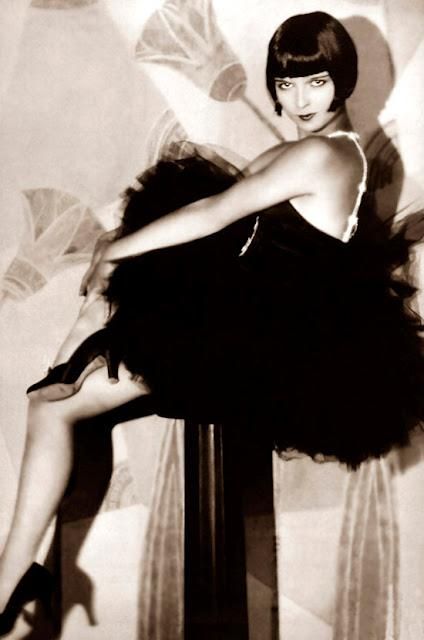 an old fashion photo of a woman in a black dress and high heeled shoes