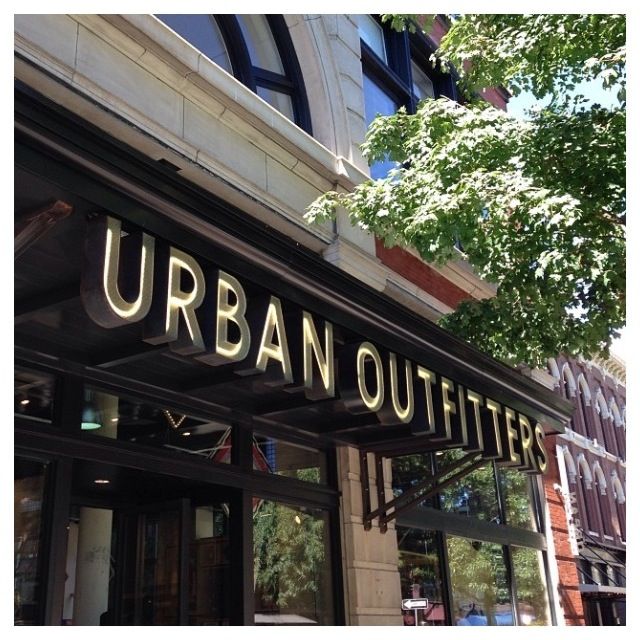 an urban outfitter store front on a city street with trees in the foreground