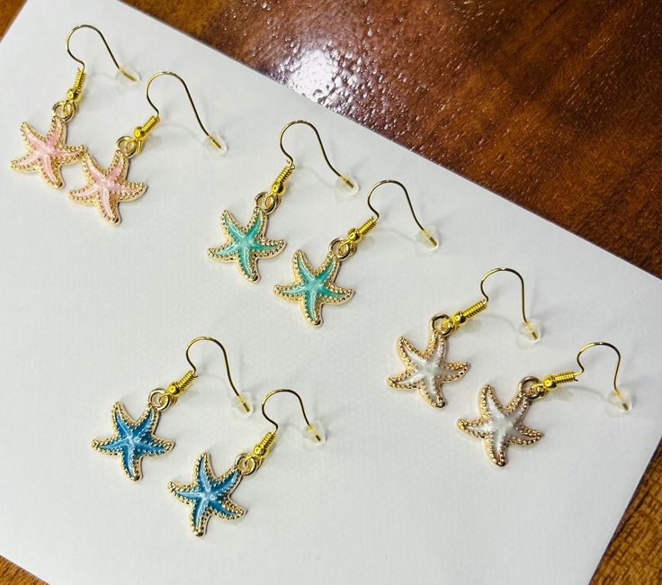 Colourful starfish-shaped earrings that are perfect for the beach! Available in a range of beach-ey, pastel colours, these gorgeous earrings glisten around the edges to enhance their fun shape. Browse our other starfish and shell themed earrings for more selection! Star-shaped Earrings For Beach With Pierced Ears, White Starfish Earrings For Beach, Ocean-inspired Star Earrings For The Beach, Star-shaped Earrings For The Beach, Ocean-inspired Star Earrings For Beach, Star-shaped Ocean-inspired Earrings For Beach, Summer Beach Earrings With Starfish Charm, Star-shaped Summer Beach Earrings, Ocean-inspired Starfish Earrings For Summer