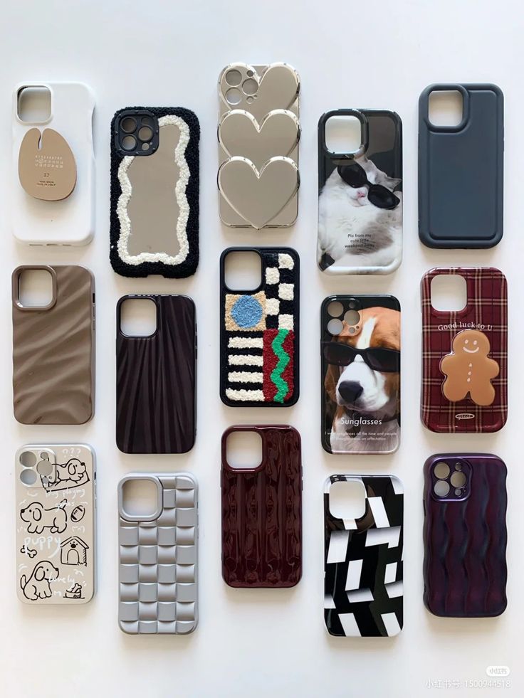 there are many different cell phones on the white surface, one has a dog and another has a teddy bear