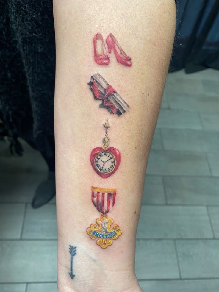 Color Wizard of Oz symbols vertical line on forearm Wizard Of Oz Symbols, Elphaba And Glinda Tattoos, Wizard Of Oz Tattoo Ideas, Tiny Wizard Of Oz Tattoo, The Wizard Of Oz Tattoos, Wizard Of Oz Quote Tattoo, Wizard Of Oz Tattoo Black And White, Wizard Of Oz Sleeve Tattoo, Tattoo Wizard