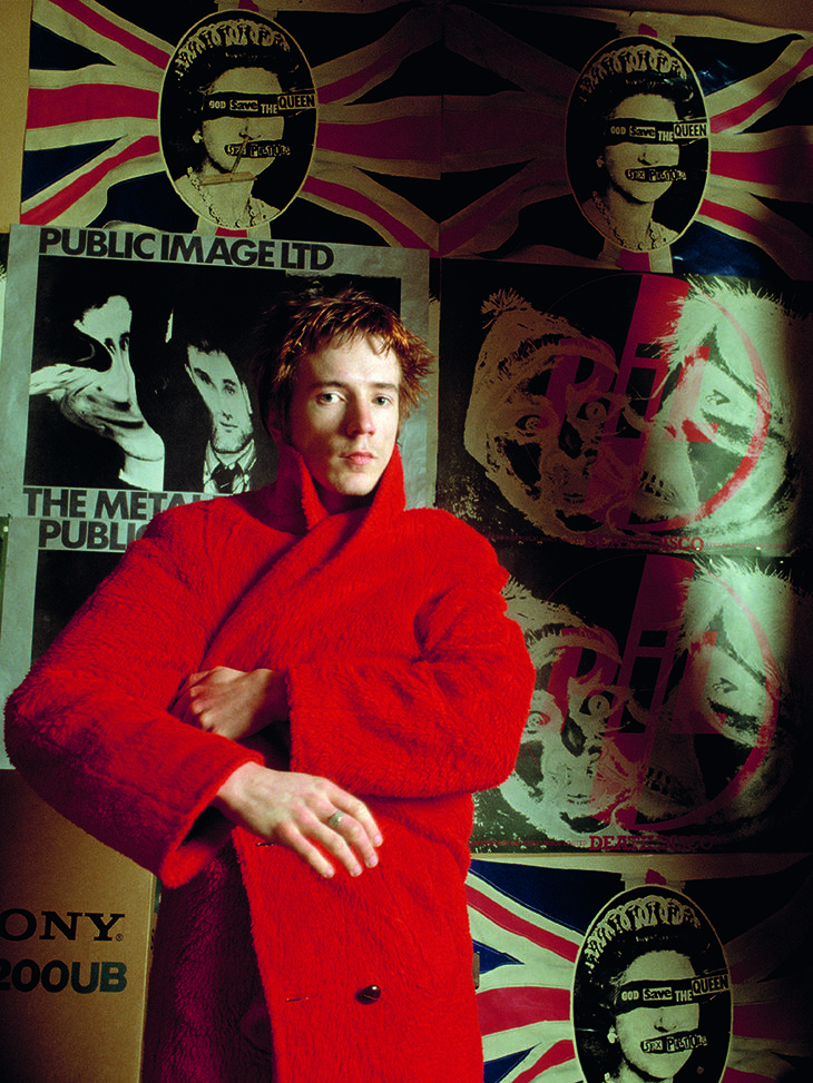 a man in a red coat is standing with his arms crossed