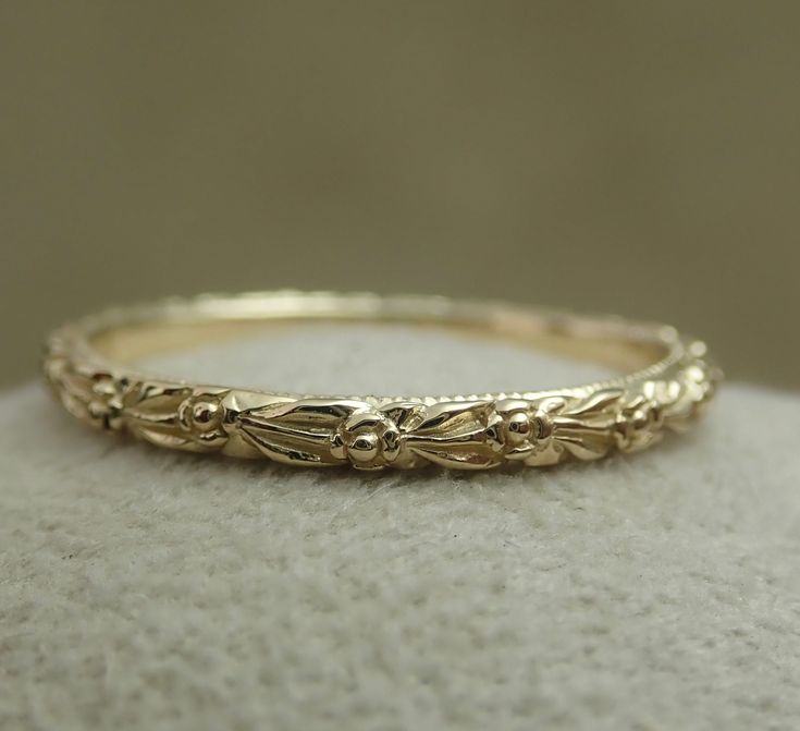 a gold wedding band on top of a white cloth covered surface with the word love written across it