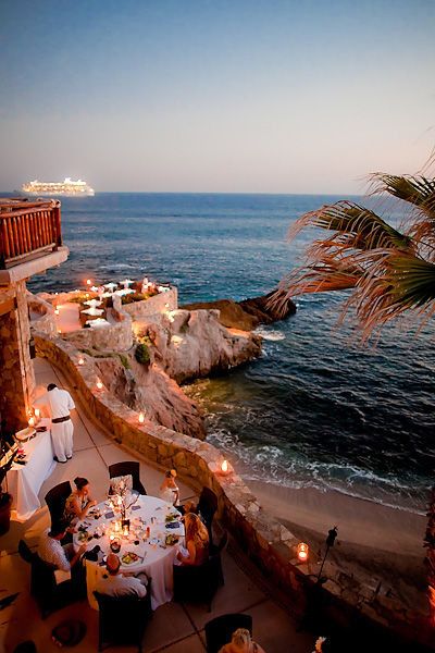 an outdoor dining area overlooking the ocean at dusk