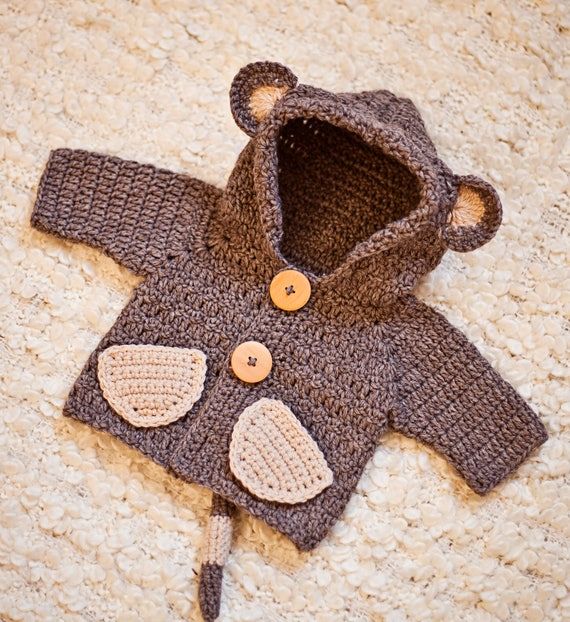 a crocheted teddy bear jacket laying on the floor