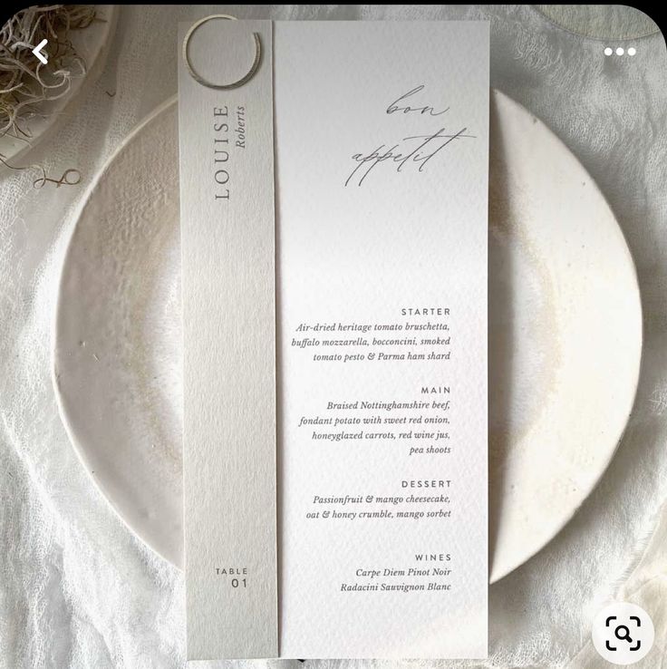 a white plate with a silver ring on top of it next to a menu card