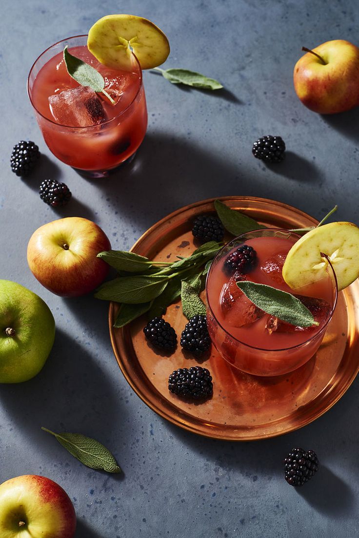 two glasses filled with fruit and garnish on top of a metal platter