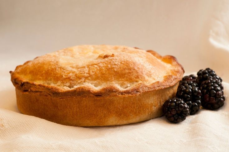 a pie and some blackberries on a white cloth