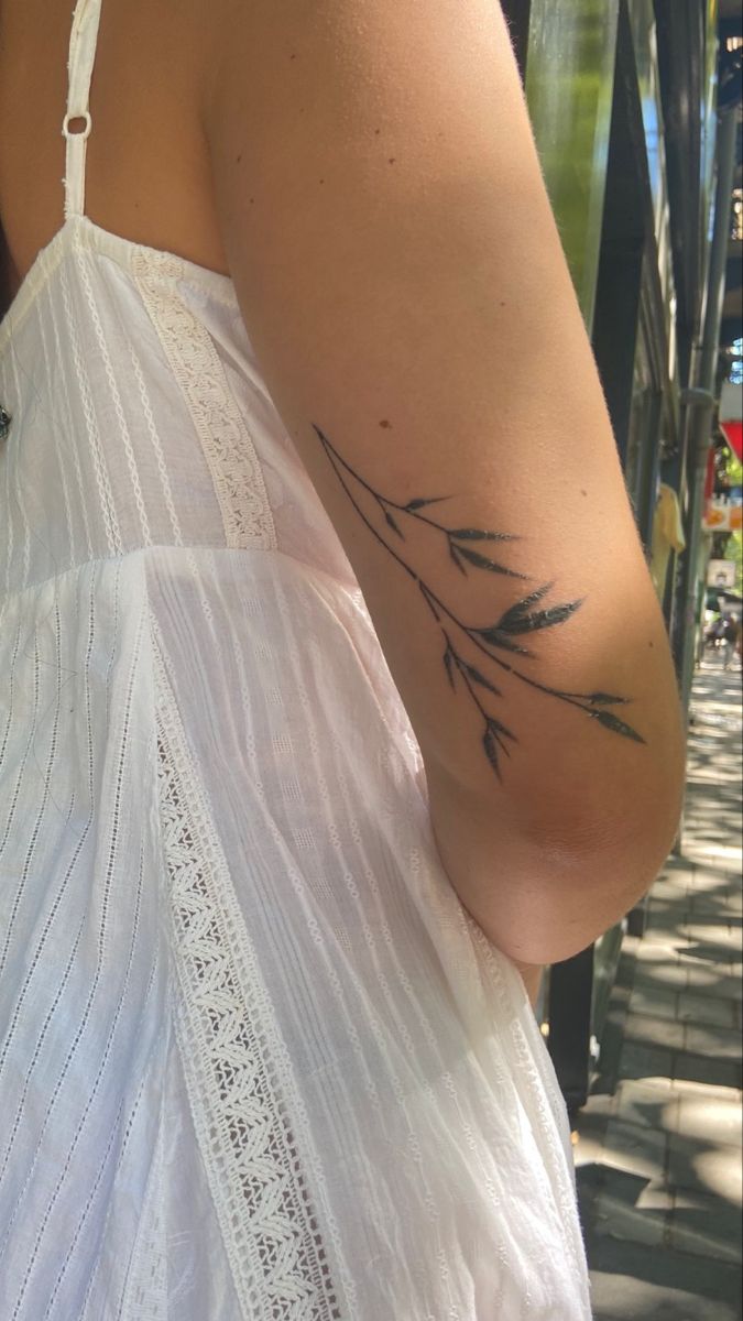 the back of a woman's left arm with an arrow tattoo on her left shoulder