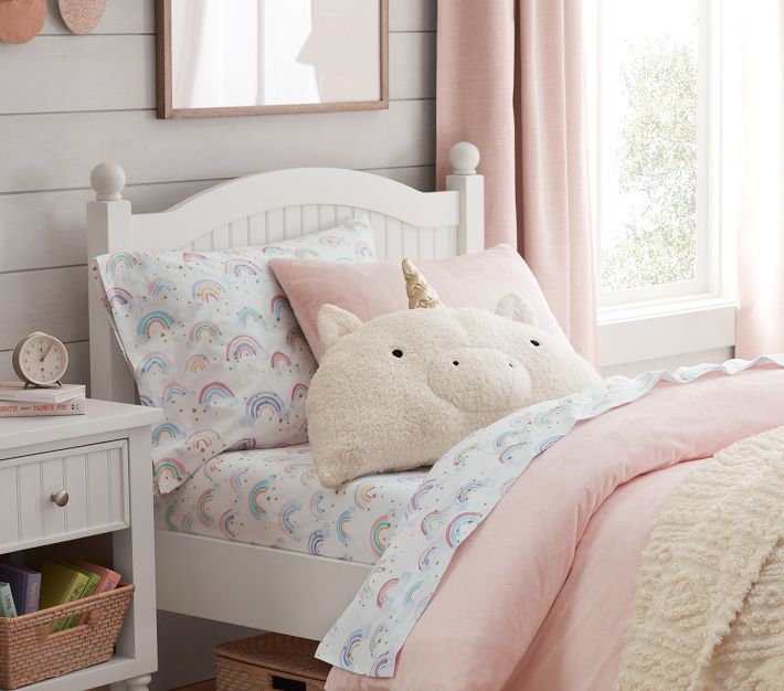 a white bed topped with pillows and a pink comforter next to a window covered in curtains