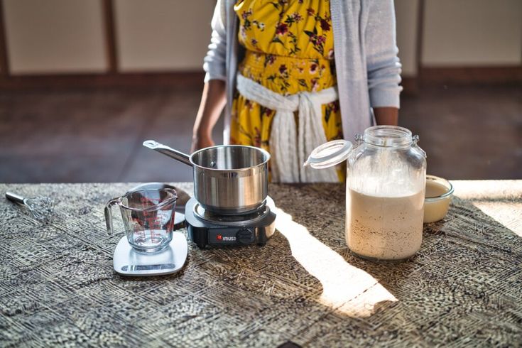 a woman standing next to a blender on top of a table with food in it