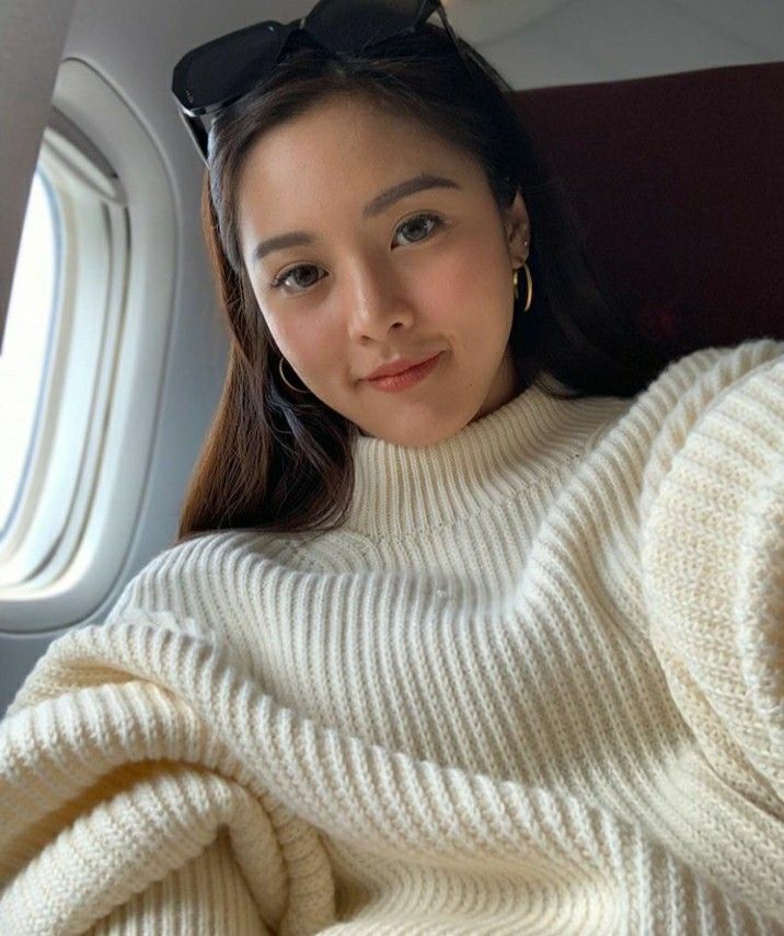 a woman wearing sunglasses sitting on an airplane