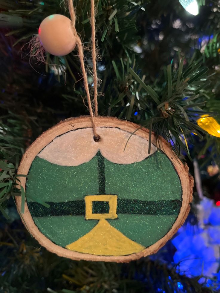 a wooden ornament hanging from a christmas tree decorated with green and yellow decorations