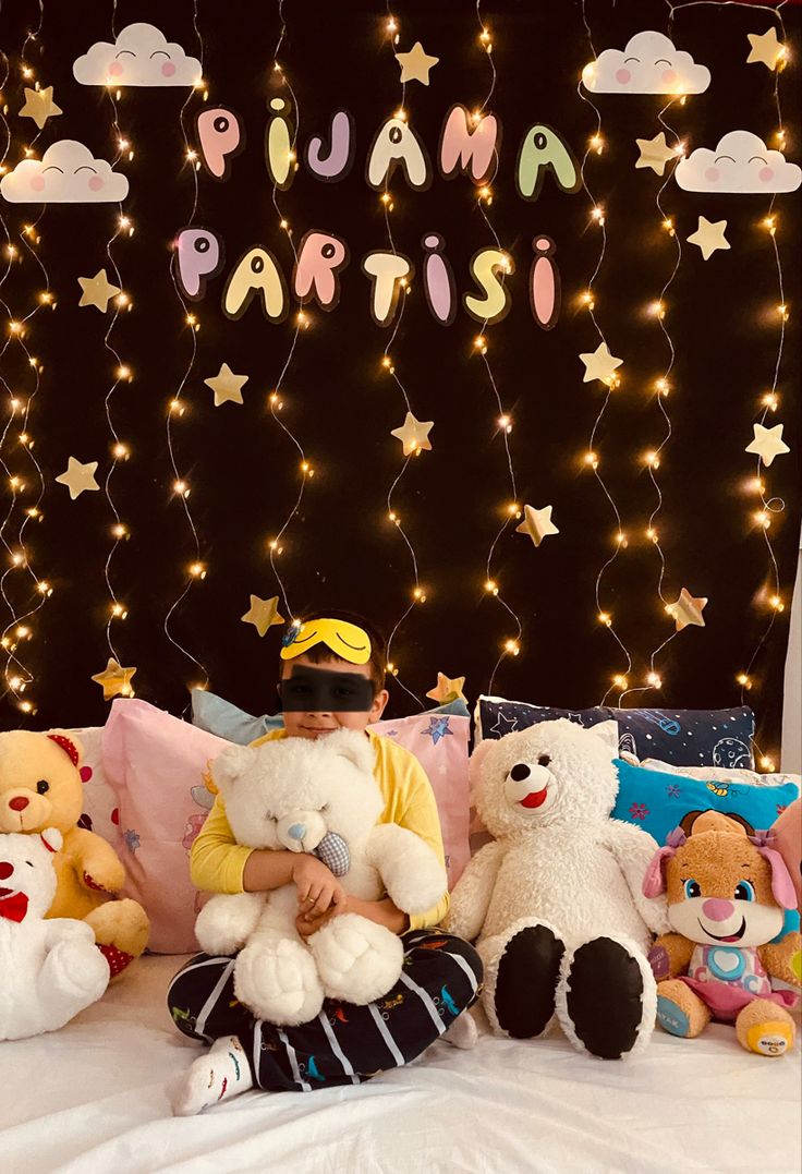 a little boy sitting on top of a bed surrounded by stuffed animals and lights that spell out the word juana paris