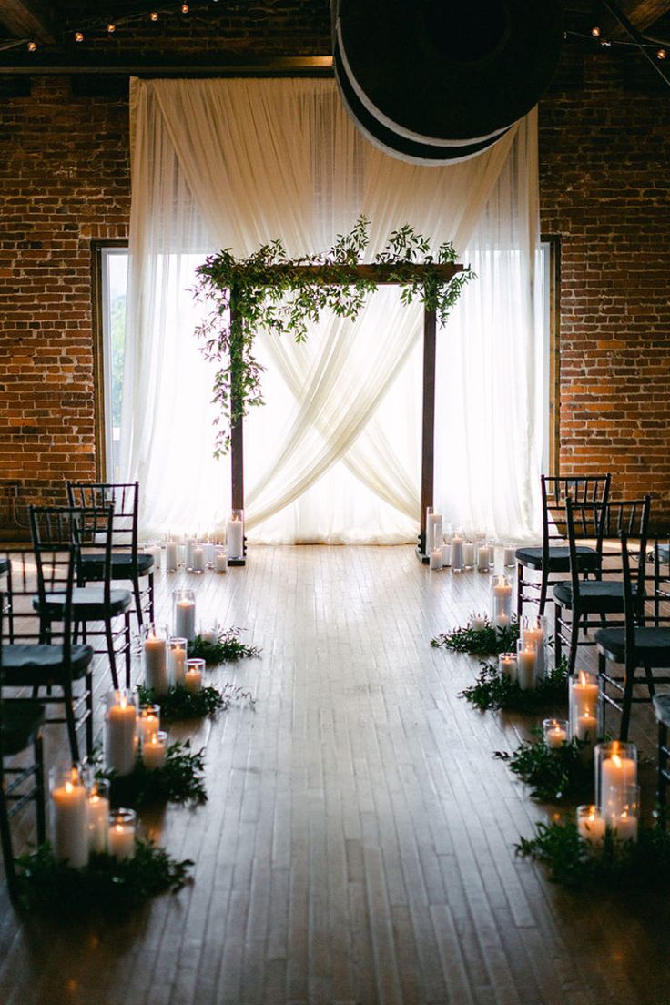 an indoor wedding setup with candles and greenery