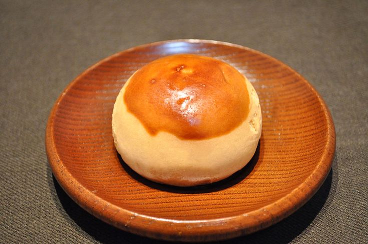 a small round pastry sitting on top of a wooden plate