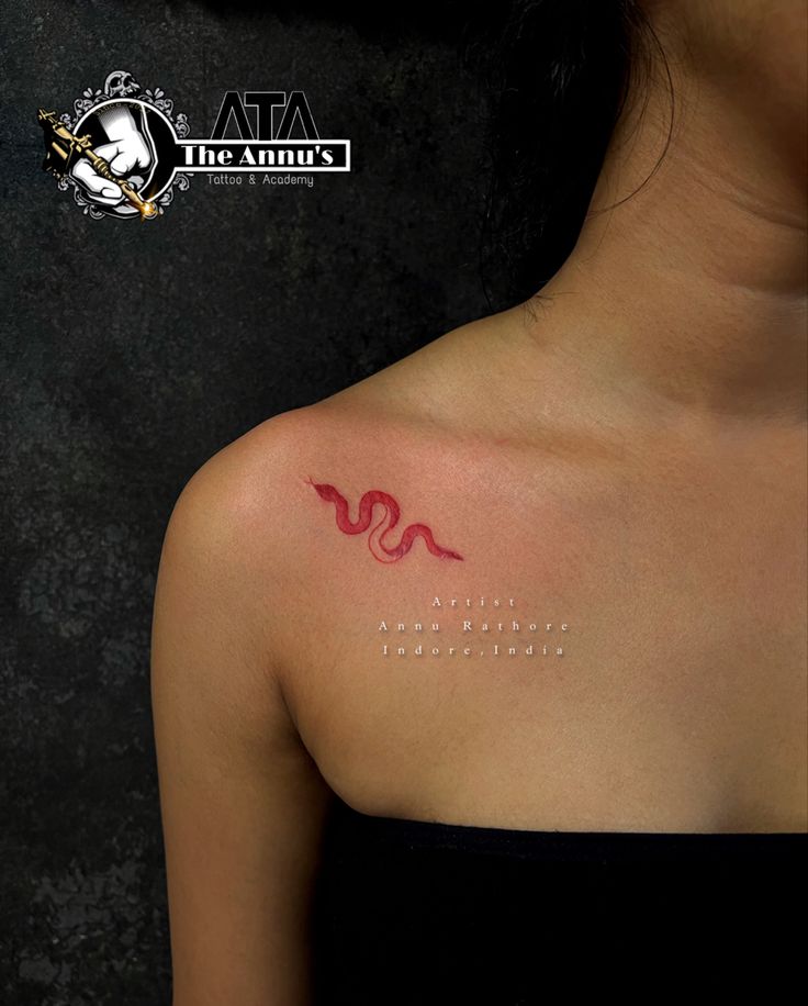 a woman with a red tattoo on her shoulder and arm, showing the letter s