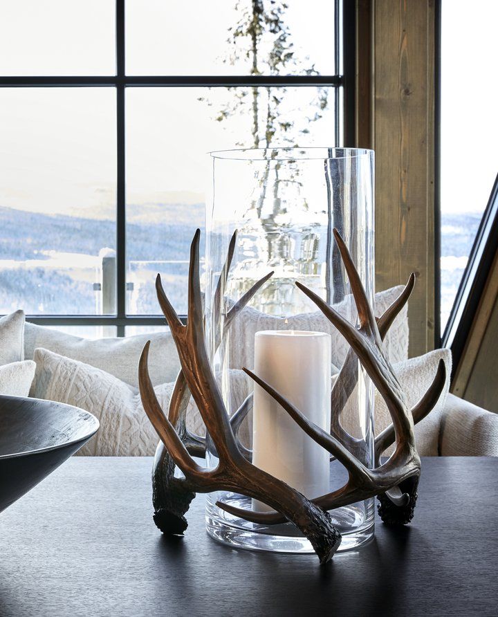 a table with candles and deer antlers on it in front of a large window