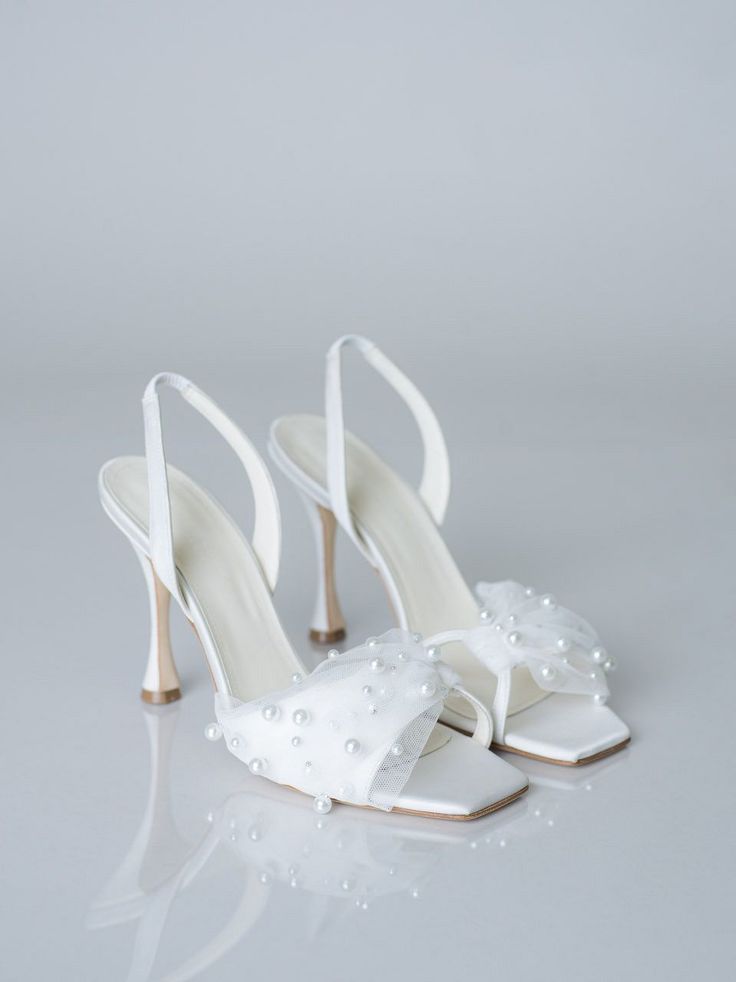 a pair of white high heel shoes with pearls on the toe and heels are shown