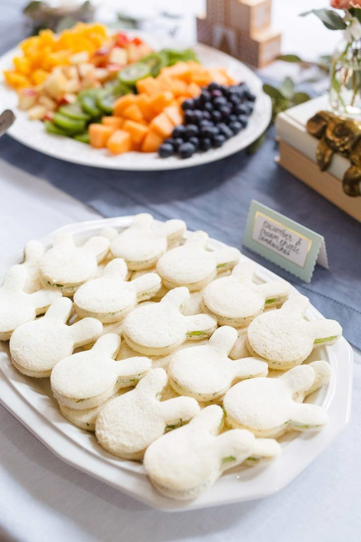 a table topped with plates filled with desserts next to flowers and fruit on top of a table