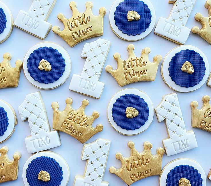 cookies decorated with royal blue and gold icing are arranged on a white tablecloth