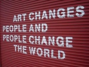 the words art change people and people change the world painted on a red garage door