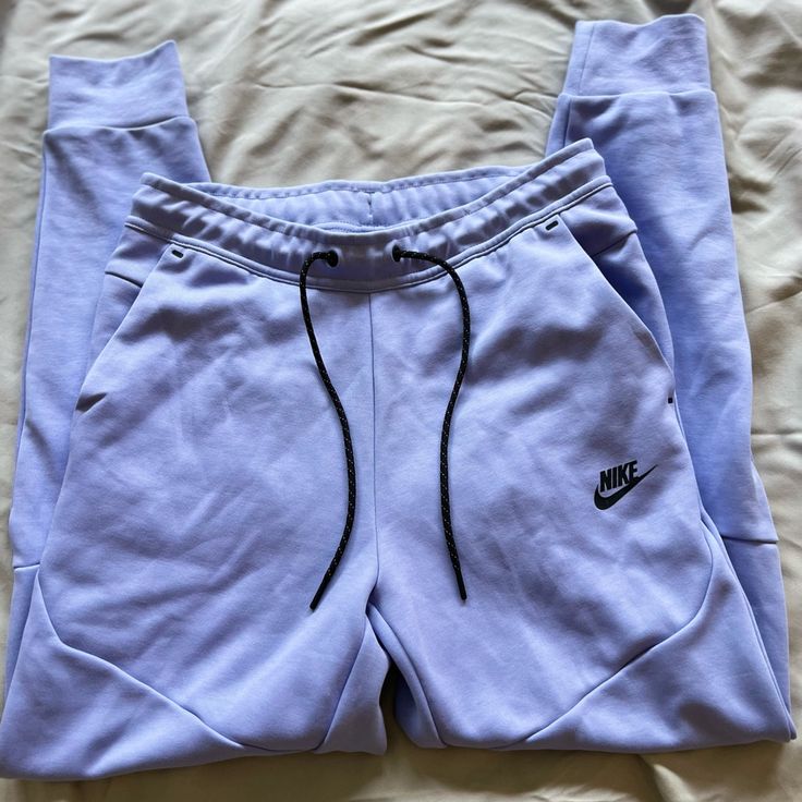 Lavender Purple Nike Tech Pants Athleisure Purple Pants With Pockets, Purple Sweatpants With Pockets For Spring, Purple Athleisure Bottoms For Spring, Spring Purple Sweatpants With Pockets, Spring Purple Athleisure Bottoms, Casual Lavender Pants With Pockets, Nike Purple Athleisure Bottoms, Sporty Purple Pants For Spring, Purple Sweatpants With Pockets For Loungewear