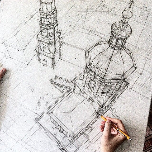 a person is drawing on paper with a pencil and some type of building in the background