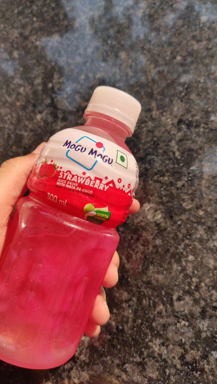 a hand holding a bottle of water on top of a counter