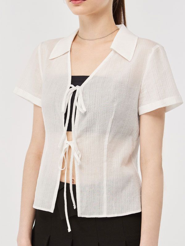 Editor's Notes This blouse is made of cotton. It features a tie detail, embroidery logo detail on the hem, collar detail, and slim waist detail which makes the blouse more feminine and lovely. Wear this item with any bottom. - Classic design short-sleeve blouse- Stylish item and a slim fit- Semi-see-through detail- Must-have item and easy to coordinate Measurements(in.)Size (S/M) - Total length: 21.06 in. / 21.45 in. - Shoulder: 14.96 in. / 15.35 in. - Chest: 17.32 in. / 18.30 in. - Waist: 14.37 in. / 15.35 in. - Hem: 17.32 in. / 18.30 in. - Sleeve length: 6.30 in. / 6.70 in. - Sleeve width: 7.28 in. / 7.48 in. - Sleeve hem: 6.70 in. / 6.88 in. *Model info: Nika Height 5'70, Bust 30 in., Waist 23 in., Hips 35 in., Wearing S, Chic Cotton Tie Neck Top, Casual Fitted Blouse With Tie Neck, Casual Fitted Tie Neck Blouse, Fitted Tie Neck Top For Day Out, Summer Cotton Tie Neck Top, Fitted Tie Neck Blouse For Summer, Summer Fitted Tie Neck Blouse, White Tie Neck Cotton Top, Summer Daywear Tops With Tie Neck