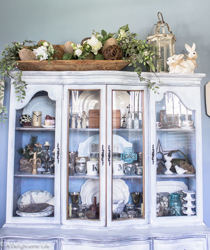 a china cabinet with glass doors and flowers on top