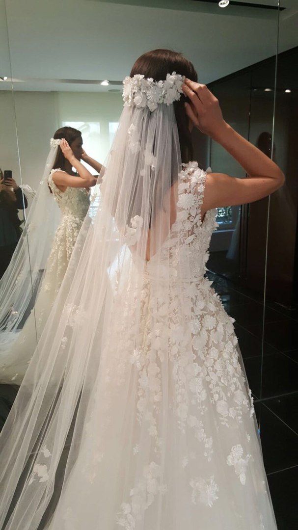 the back of a bride's wedding dress in front of a mirror with flowers on it