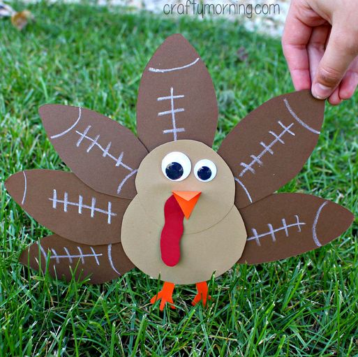 a hand holding a paper turkey on the grass