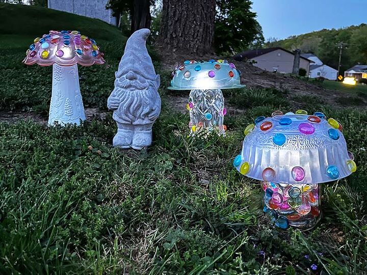 three glass mushrooms sitting in the grass next to a tree with lights on them,